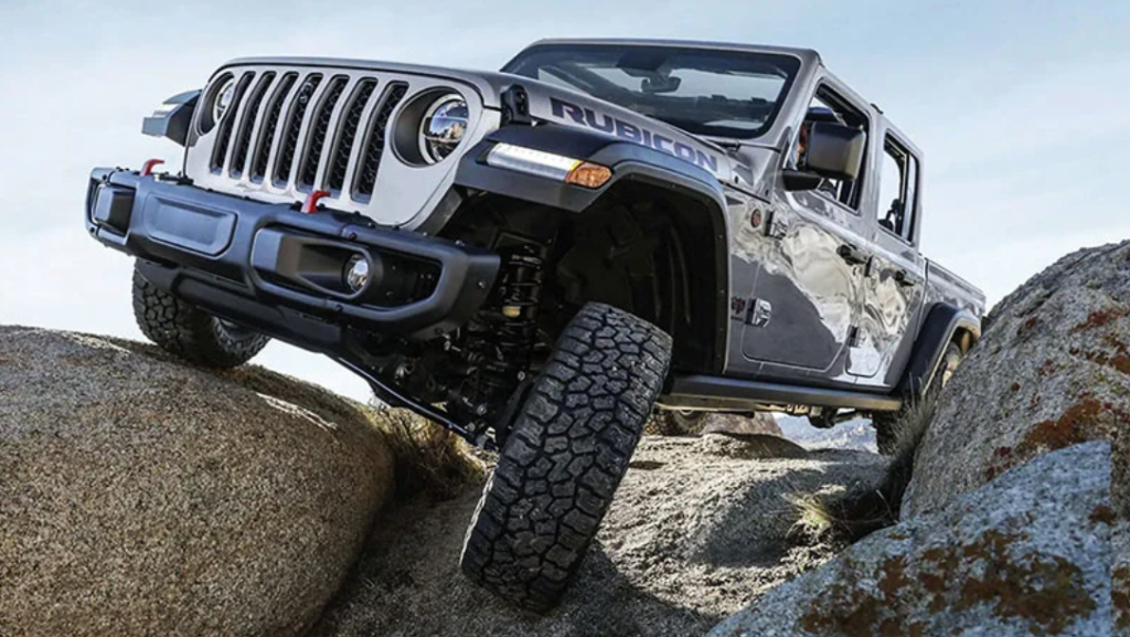 A silver 2023 Jeep Gladiator driving over rocks.