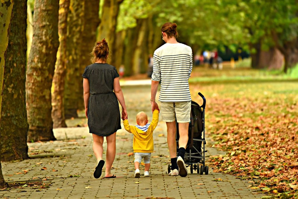 A family of three walking down a park path.