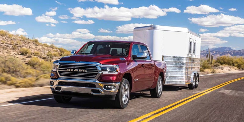 A red 2024 Ram 1500 towing a trailer.