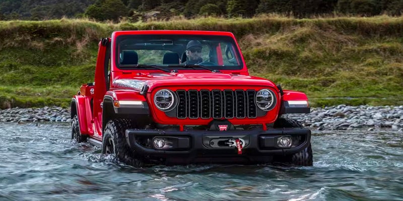 A red 2024 Jeep Wrangler driving through deep waters.